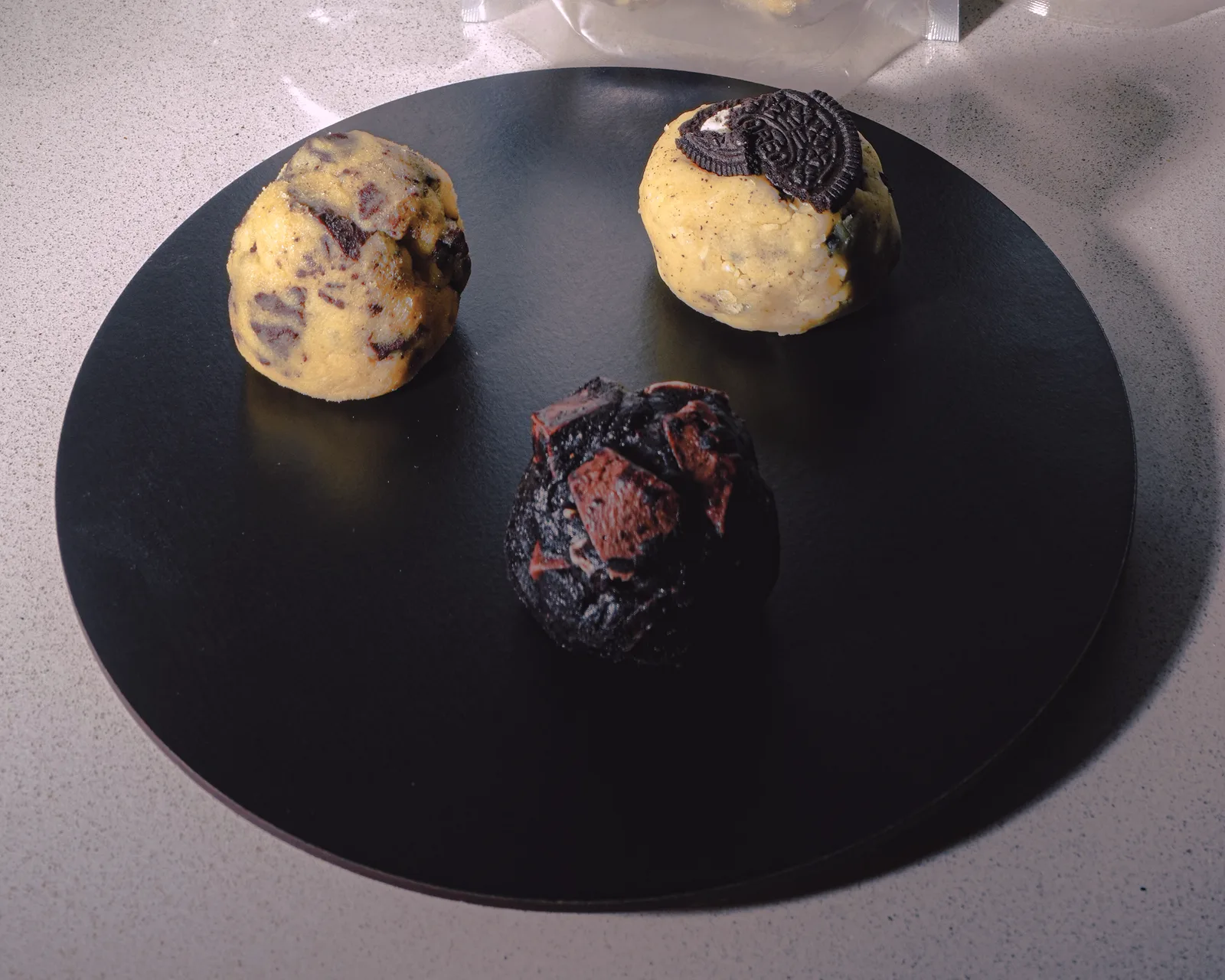 Tres bolitas de masa congelada, una de cada sabor, sobre un plato negro